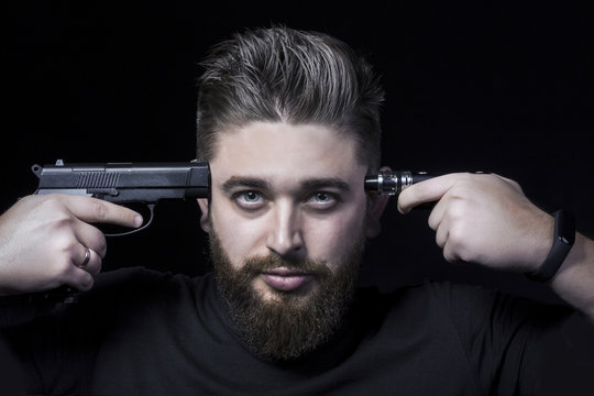 the face of a man with a pistol attached to his temple and on the other side an electronic cigarette, the concept smoking kills, close-up background