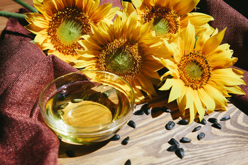 Obraz na płótnie Canvas Sunflower oil with yellow flowers and seeds on wooden background with sunshine