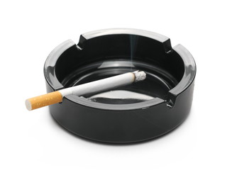 Lit cigarette in black ashtray isolated on white background