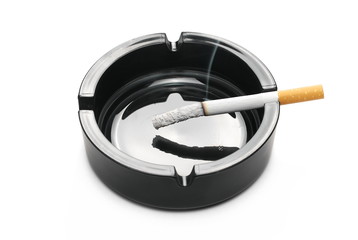 Lit cigarette in black ashtray isolated on white background