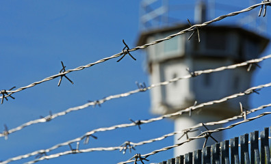 Stacheldraht mit Wachturm im Hintergrund