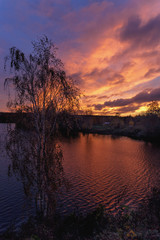 colorful sunset reflection into the calm water of a forest lake