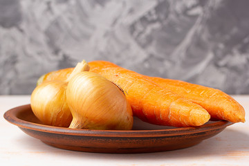 Onions, carrots in a clay plate. Copy space. Preparing fresh vegetables for cooking