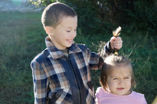 Children having fun. Boy and little girl portrait. Happy smiling children outdoors at sunny day. Friendship siblings. Brother joking on little sister