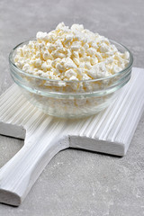 Cottage cheese in glass bowl on white wooden board