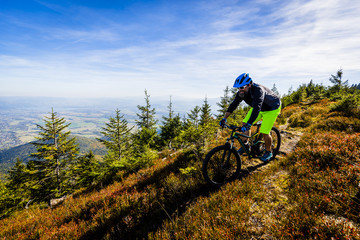 Fototapeta na wymiar Mountain biker cycling in autumn mountains forest landscape. Man cycling MTB flow trail track. Outdoor sport activity.