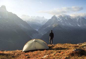 Hiker enjoying the view and a cup of coffee at his campsite in the mountains.