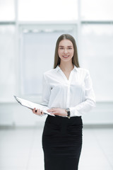 Executive business woman with clipboard against the background of bright office