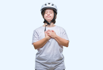 Young adult cyclist woman with down syndrome wearing safety helmet over isolated background smiling with hands on chest with closed eyes and grateful gesture on face. Health concept.