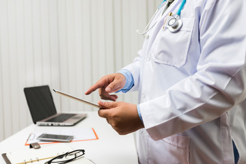 Doctor working with tablet computer at desk. Technology and medical concept.