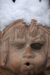 Terrakotta Gesicht mit Schnee im Garten
