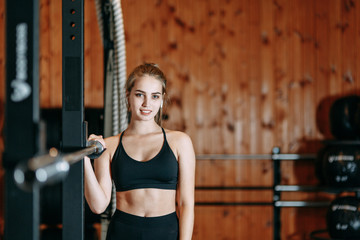 Sports girl deals with the ball and resting in the gym. Standing next to the machines and smiling.