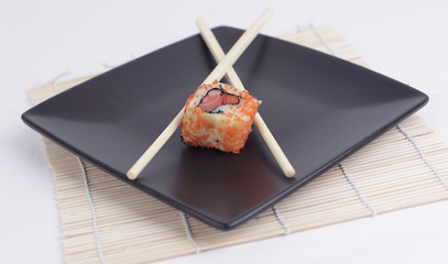 close-up of sushi and chopsticks on a black plate