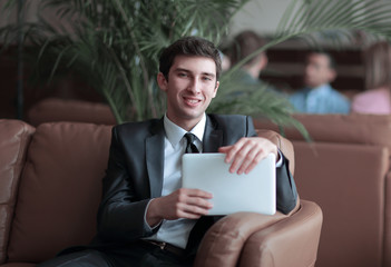 close-up of a young businessman using a digital tablet sitting in the lobby of the Bank