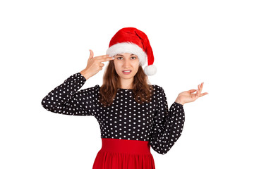 Annoyed and displeased woman in dress shrugging and holding fingers on temple. emotional girl in santa claus christmas hat isolated on white background. holiday concept