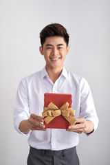 Young adult businessman holding gift box and looking at camera and toothy smile. On white background. Studio shot