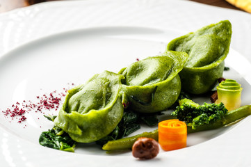 Green Ravioli with quail egg on a black background. A Halloween Feast.