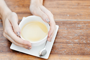Female hands holding a cup of herbal or green tea, top view, copy space