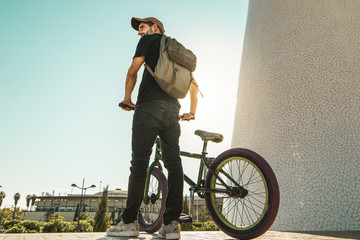 Young man with a bmx bike and a backpack in the city