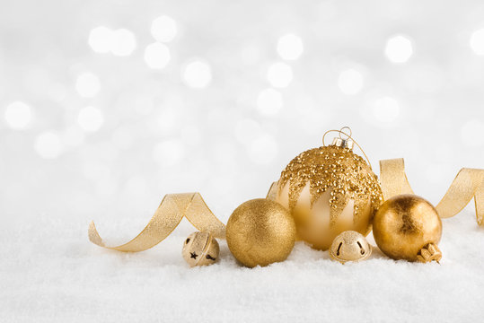 Christmas golden balls on snow over abstract winter lights background