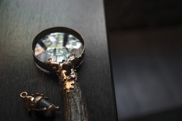 Loupe close-up, vintage magnifier handmade on dark wooden table background, concept of search, investigation, private detective, lawyer, important details, copy space, top view
