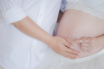 Fototapeta na wymiar An Expecting parents holding wedding ring. pregnant woman