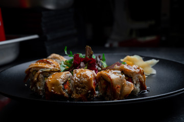 Roll with eel on a black plate in the kitchen of a pan-Asian restaurant.