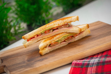 Classic sandwich with ham and vegetables on a wooden board.Класический сэндвич с ветчиной и овощами на деревянной доске.