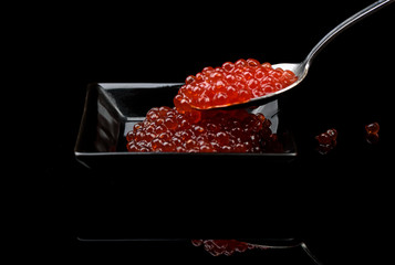 Caviar in bowl over black background with reflection