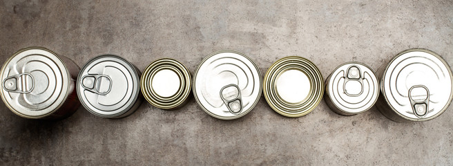 Botes de conserva de comida formato panorámico sobre un fondo gris. Vista superior