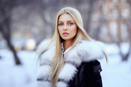 Young woman in fur coat standing outside