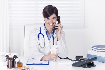 Smiling young female doctor talking on a telephone