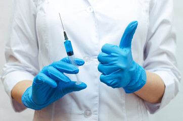Syringe with a blue medical drug and doctor hand which showing a thumbs up sign. The best medical drug concept.