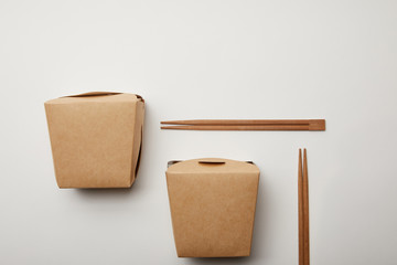 flat lay with arranged wok boxes and chopsticks on white surface, minimalistic concept