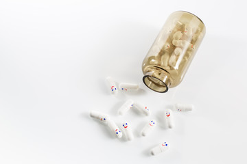 Glass bottle with fun painted emotions on the capsules. View from above.