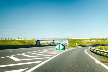 French autoroute highway exit on the right with security differentiator and overpass - clear blue sky to great holidays - obrazy, fototapety, plakaty