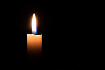 A candle brightly lit in a dark room yellow flame