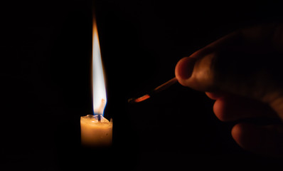Person lighting a candle with a matchstick. extinguised matchstick