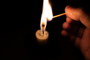 Person lighting a candle with a matchstick.