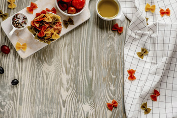 Fototapeta na wymiar Pasta food cooking concept. Ingredients for preparation pasta - tomato, olive oil, spices, olives, tomato, grey wooden background. Top view with copy space for text.
