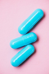 close-up shot of blue medical capsules on pink