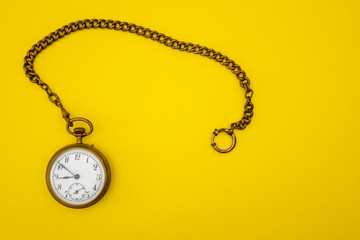 Pocket vintage gold watch on a yellow background.