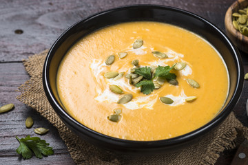 Pumpkin soup on dark wooden table.