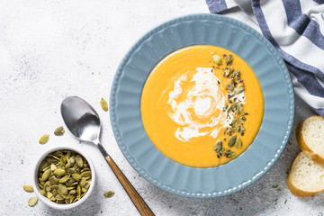 Pumpkin cream soup on light stone table.
