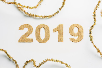 top view of 2019 year sign made of golden glitters and garlands on white backdrop