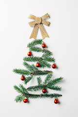 top view of green pine branch decorated as festive christmas tree with bow on white background