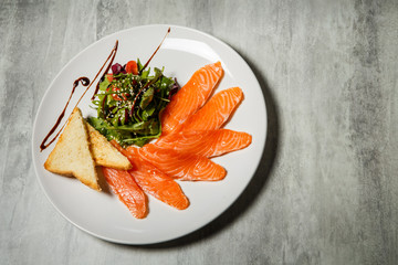 salmon slices served with rucola and tomato salad and toasted bread