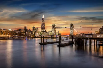 Poster Blick auf die Tower Bridge an der Themse und die beleuchtete, urbane Skyline von London bei Sonnenuntergang, Großbritannien © moofushi