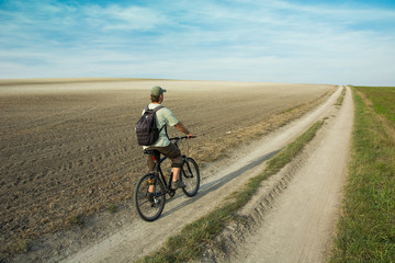 Naklejka na ściany i meble Man traveler with a backpack on a bike
