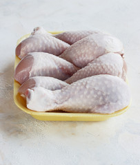 fresh raw chicken pieces on a light background in a tray